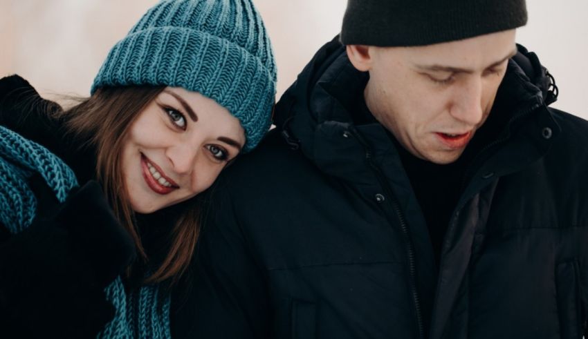 A man and a woman are standing together in the snow.