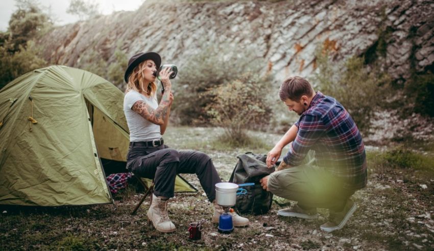 A man and woman sitting next to a tent.
