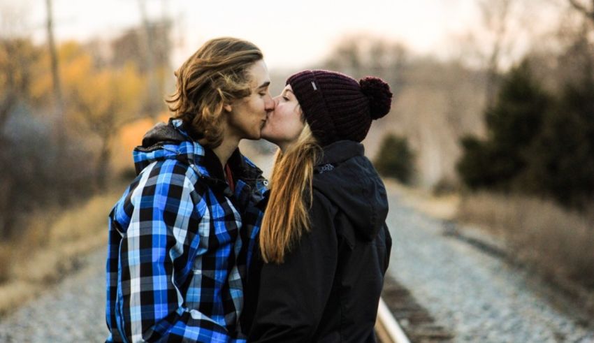 Two people kissing on a train track.