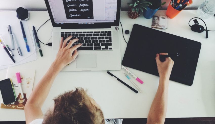 A person working at a desk with a laptop and pens.