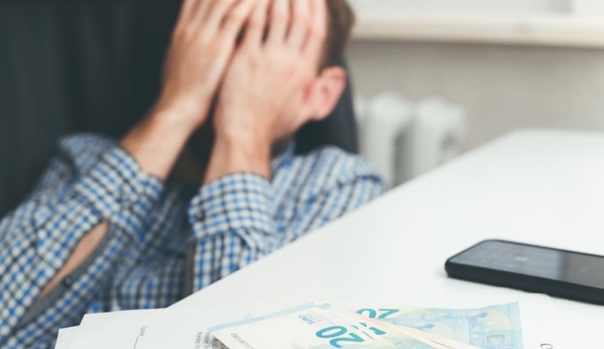 A man covering his face with money on a desk.