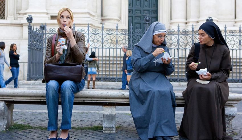 Three nuns sitting on a bench eating food.