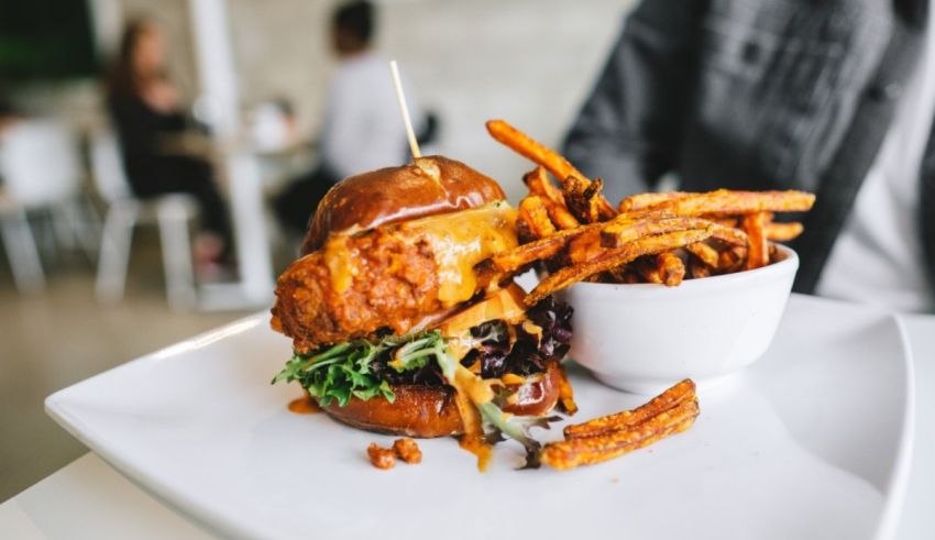 A burger with fries on a white plate.
