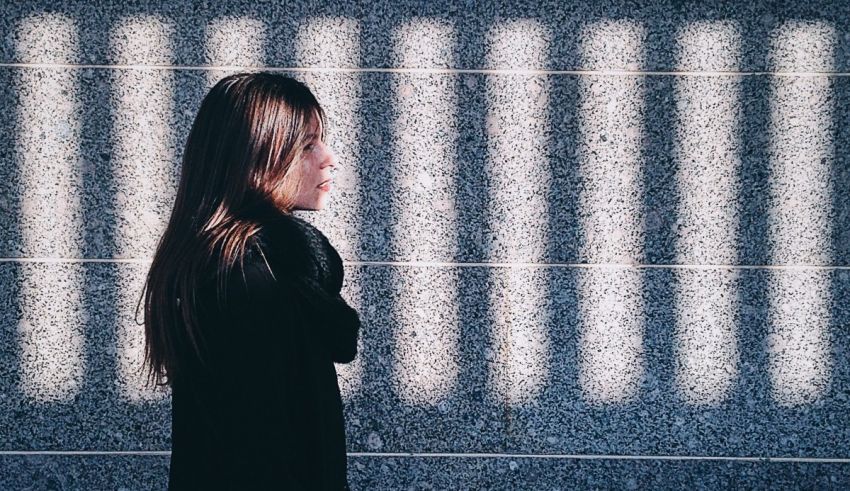 A woman standing in front of a wall with bars.