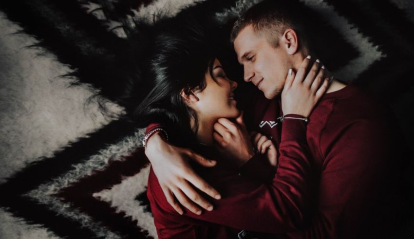 A man and woman hugging on a rug.