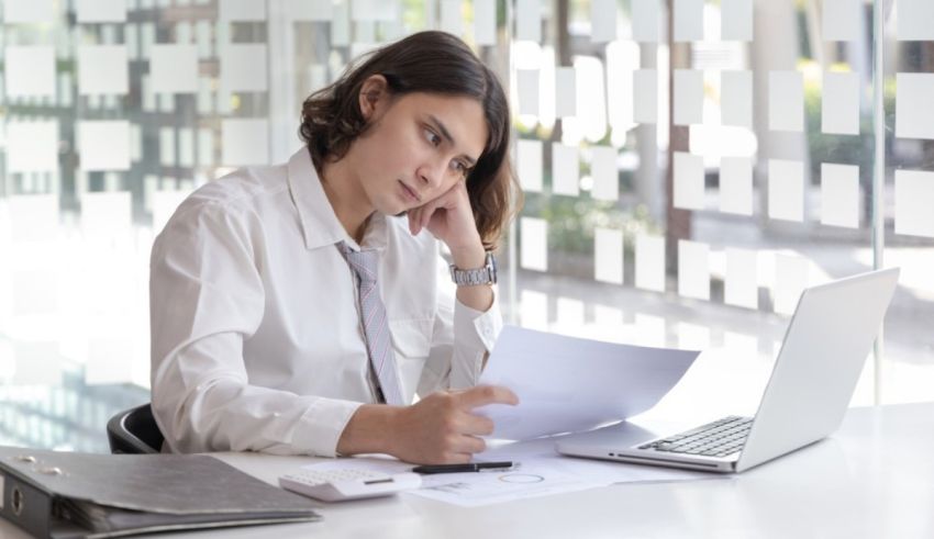 A business woman sitting at a desk with papers and a laptop.