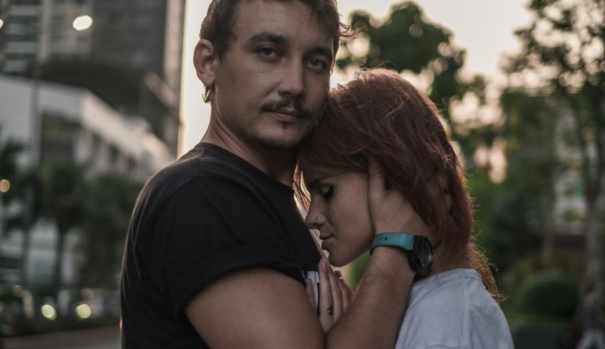 A man and woman hugging in front of a city.