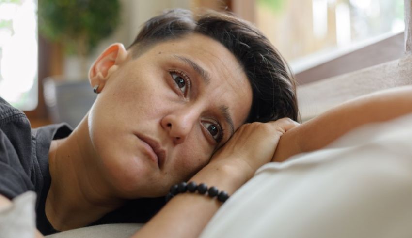 A woman laying on a bed with her head resting on her hand.
