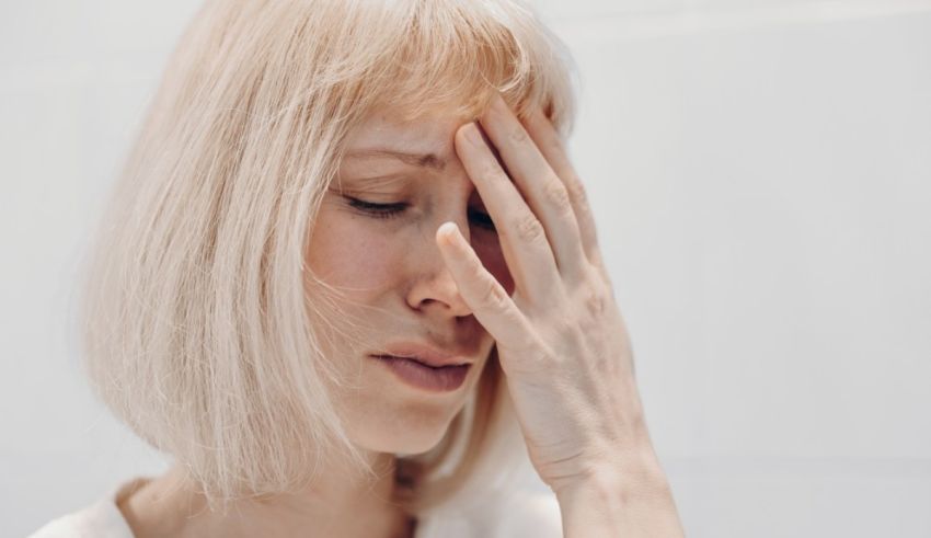 A woman with blond hair is holding her head.