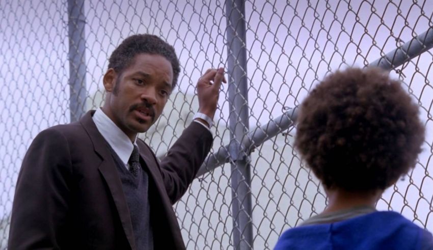 A man in a suit standing next to a fence.