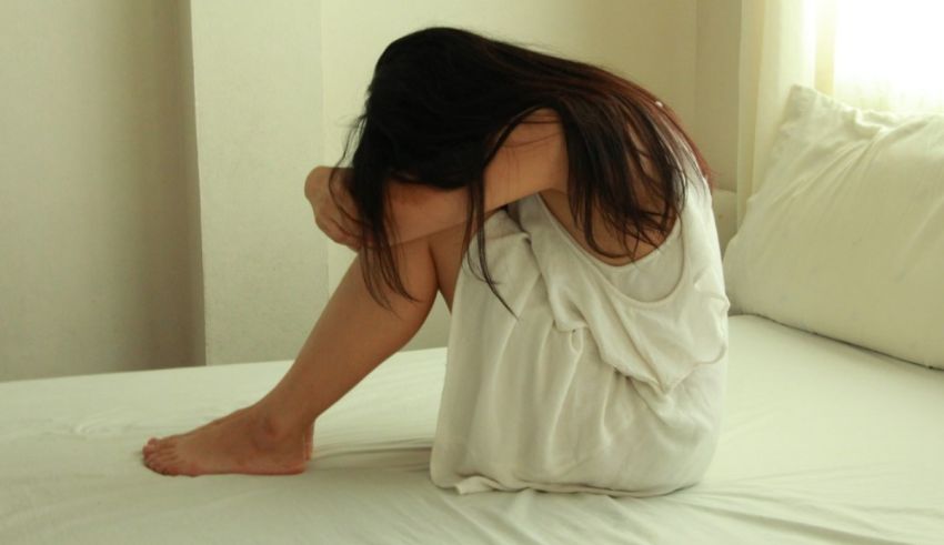 A woman sitting on a white bed.