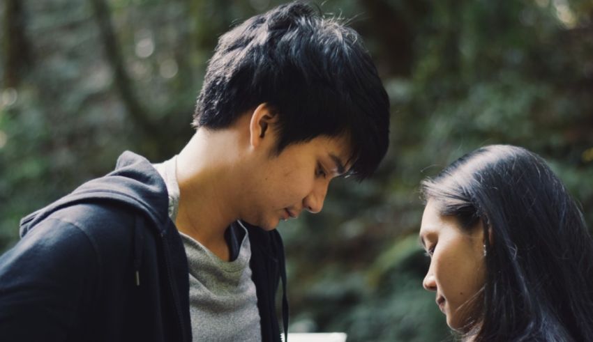 A man and woman looking at each other in the woods.