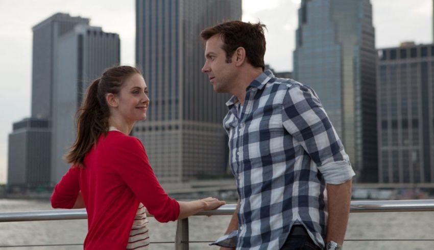 A man and woman standing on a dock in front of a city.