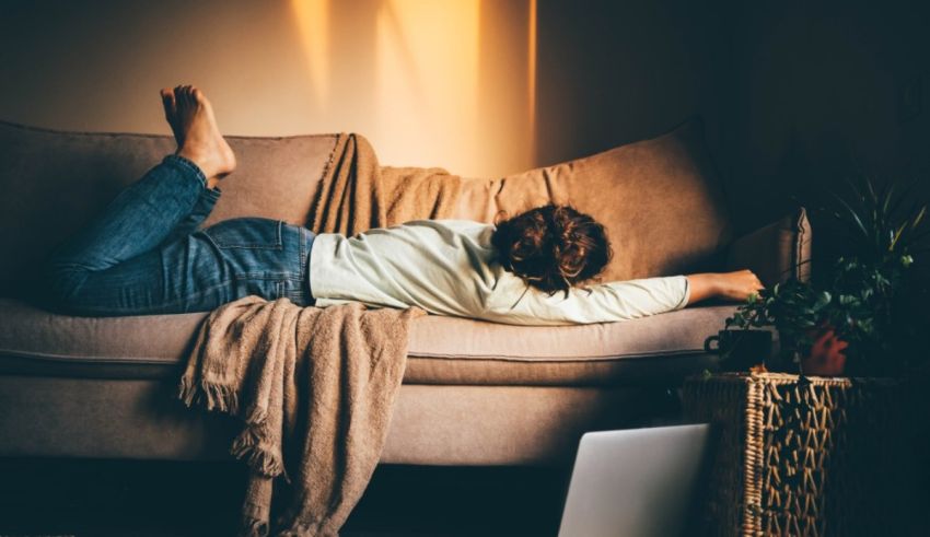 A woman laying on a couch in front of a laptop.