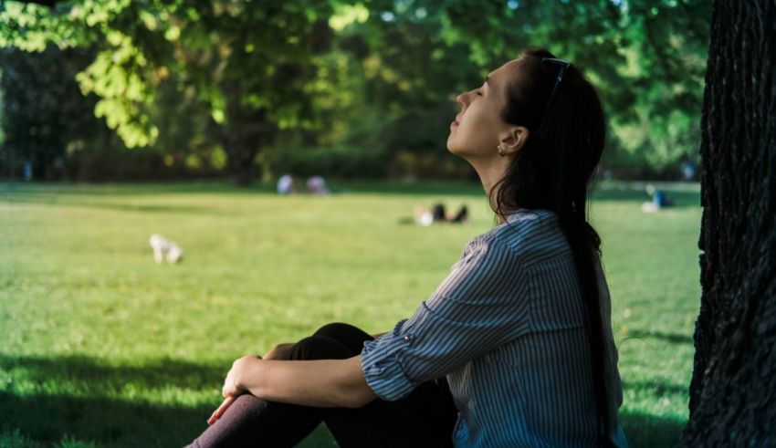 A woman sitting under a tree in a park.