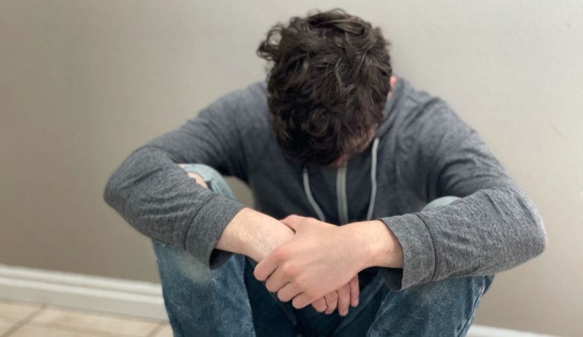 A man sitting on the floor with his hands on his knees.