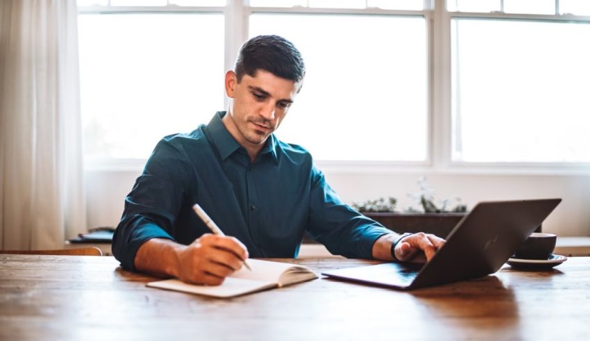 A man sitting at a table with a laptop and a pen.