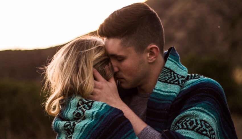 A man and woman hugging in front of a mountain.