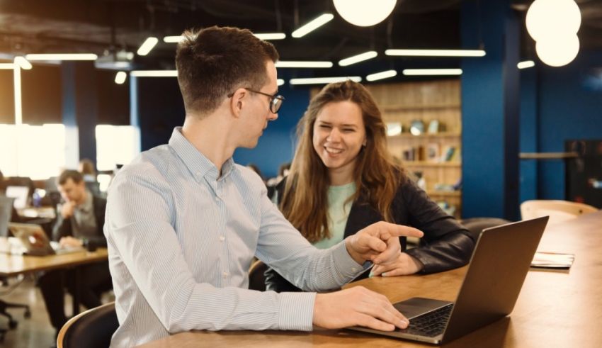 Two people sitting at a table and talking to each other on a laptop.