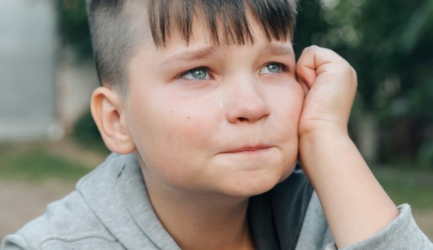 A young boy with blue hair is looking at his hand.