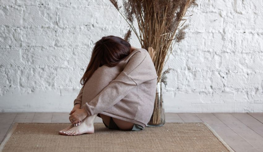 A woman sitting on a rug in front of a vase.