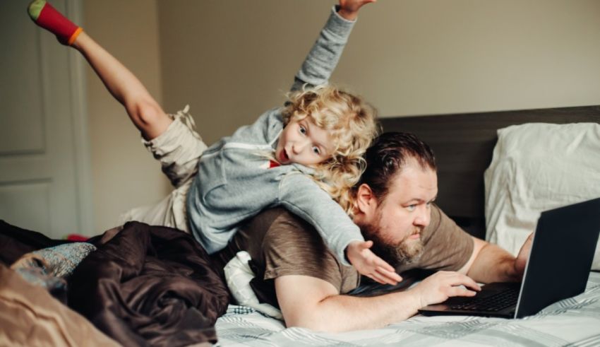 A man and a child laying on a bed with a laptop.