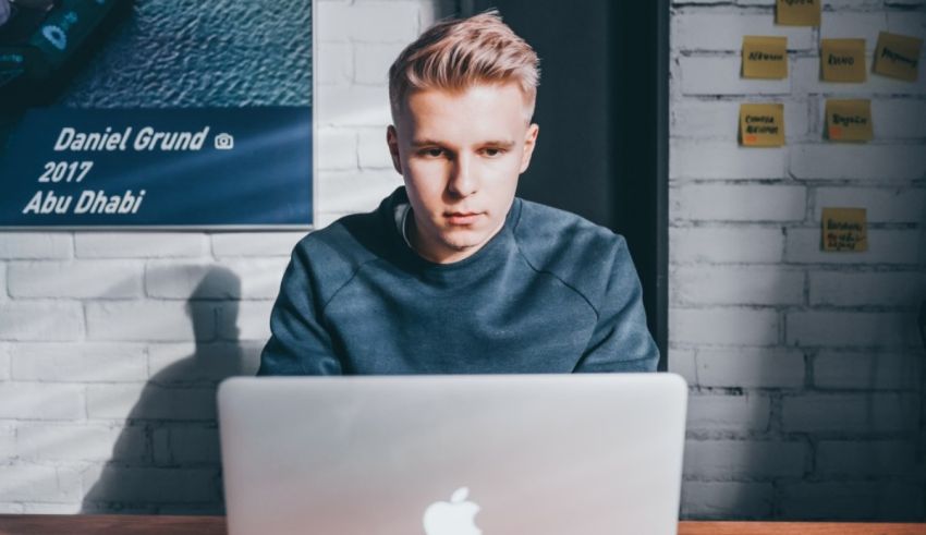 A man sitting at a desk with a laptop in front of him.