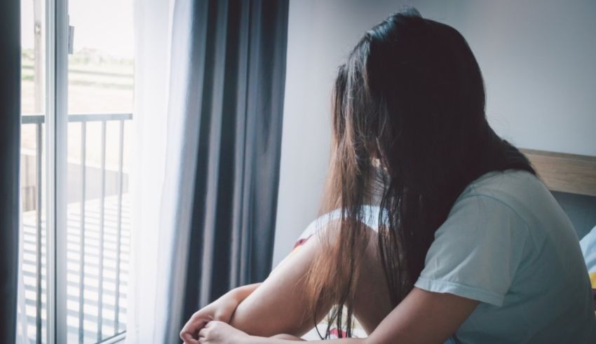 A woman sitting on a bed looking out the window.