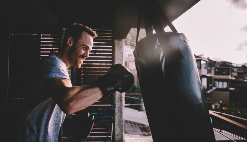 A man is punching a boxing bag in front of a window.