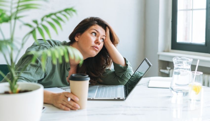 A woman sitting at a desk with a laptop and a cup of coffee.