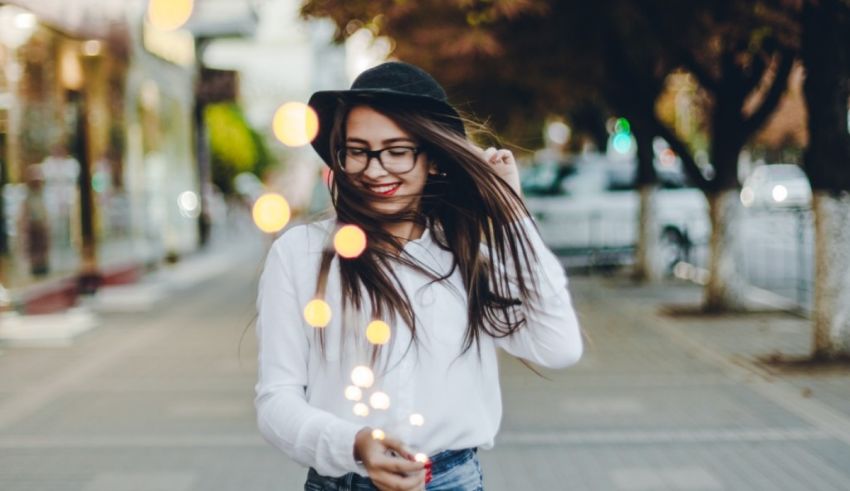 A young woman holding sparklers on a city street.