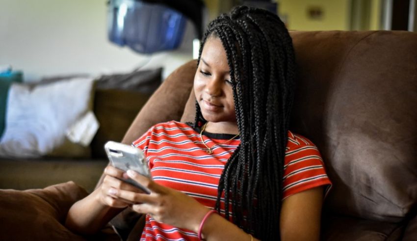A girl sitting in a chair looking at her phone.