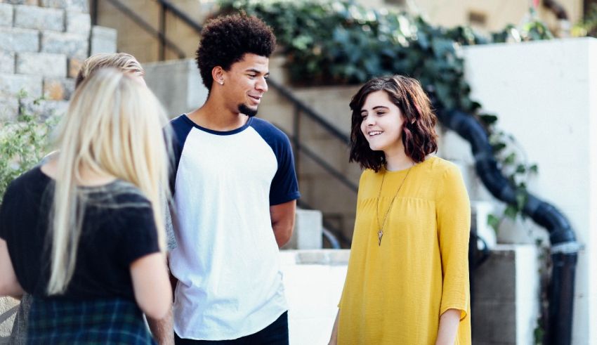 A group of young people talking to each other on a street.