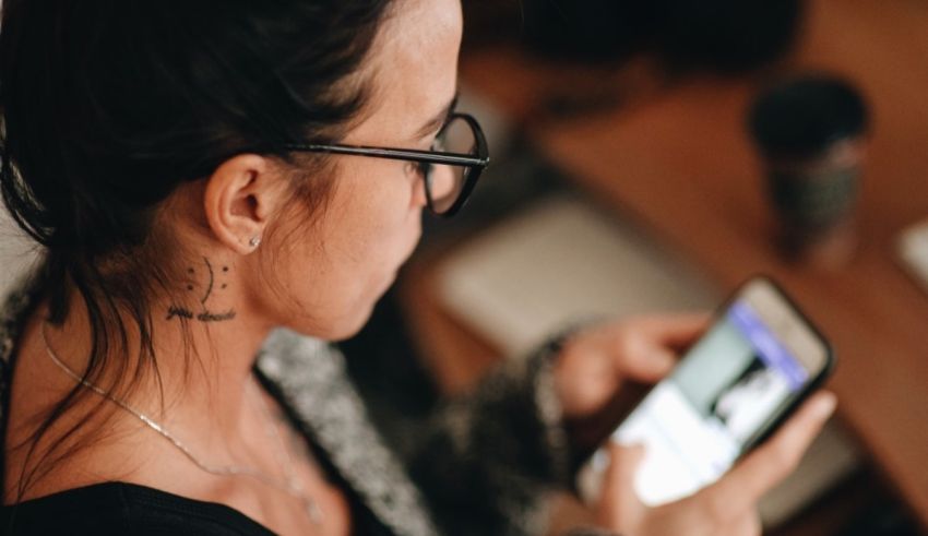 A woman is looking at her phone while sitting at a table.