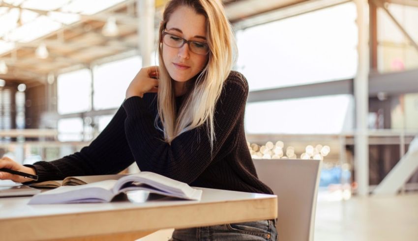 A woman wearing glasses is sitting at a table with a laptop.