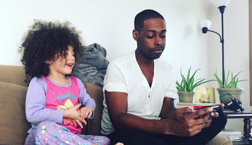 A man and a little girl sitting on a couch with a cell phone.