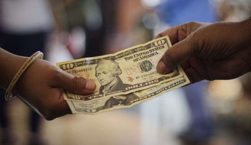 A person is handing a dollar bill to another person.