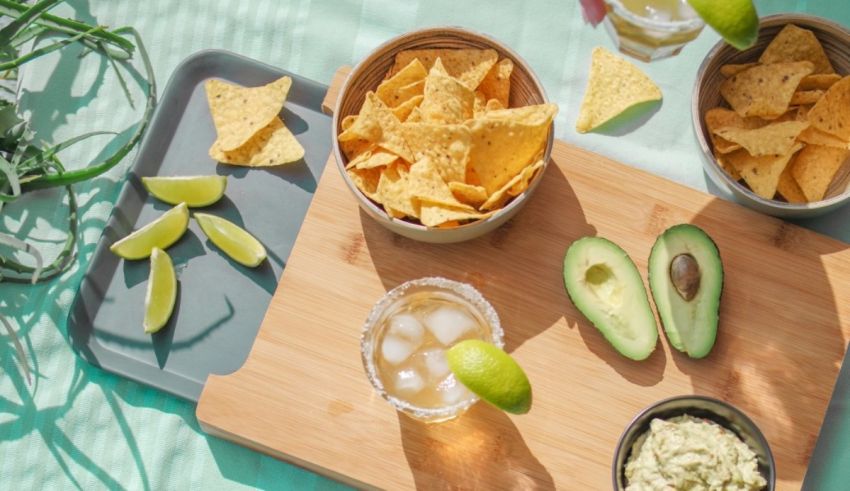 Guacamole, chips and salsa on a wooden cutting board.