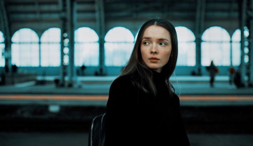 A woman in a black jacket standing in a train station.
