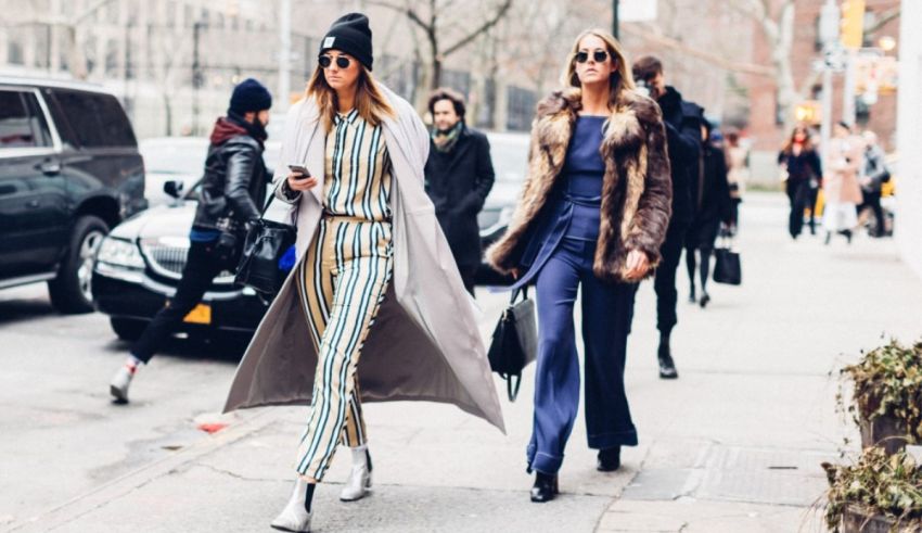 Two women walking down the street in striped jumpsuits.