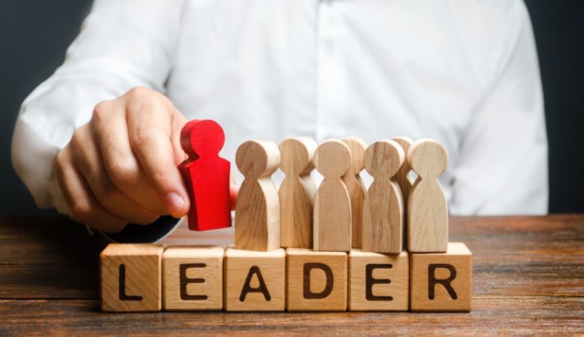 A man is putting a wooden block with the word leader on it.