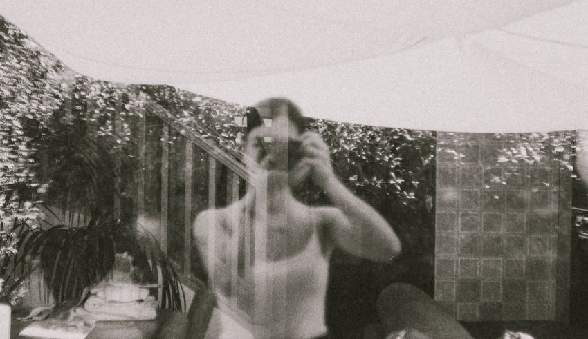 A black and white photo of a woman taking a picture.