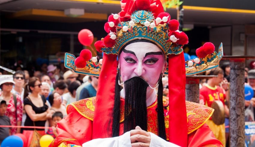 A man in a chinese costume is standing in a crowd.