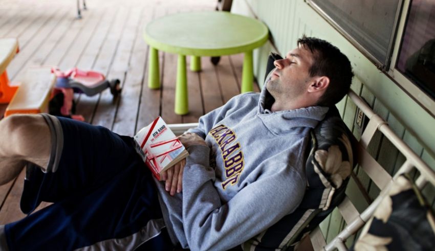 A man is sitting on a porch reading a book.