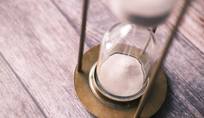 An hourglass with sand in it on a wooden table.