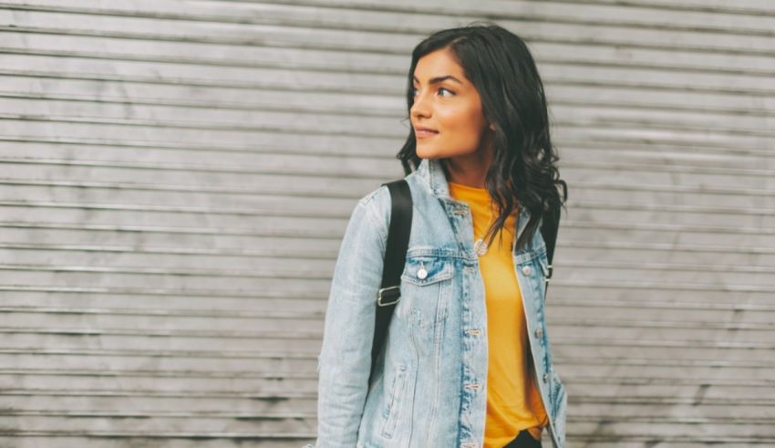 A young woman wearing a denim jacket and yellow t-shirt.