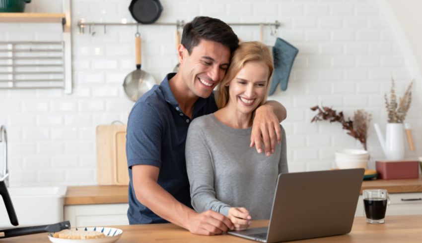A young couple using a laptop in the kitchen.
