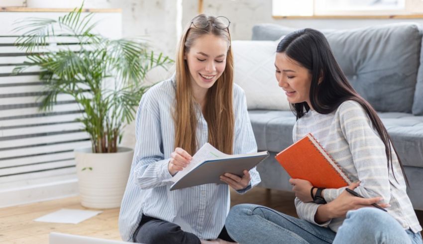Two women sitting on the floor and looking at a laptop.