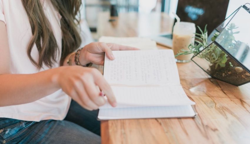 A woman writing in a notebook at a table.