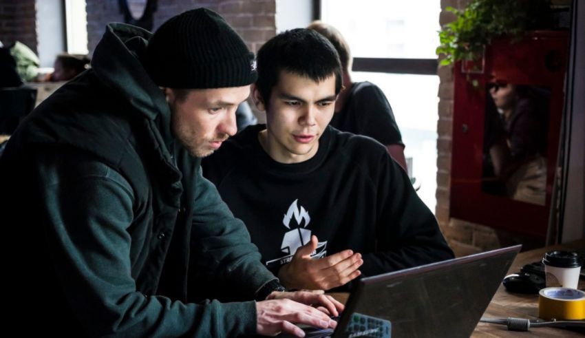 Two men working on a laptop in a coffee shop.